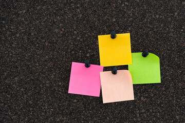 Colorful note papers on a brown cork bulletin board.