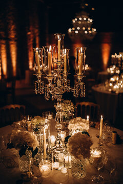 Wedding table setting and decoration. Candles and cutlery on the table. Flower decoration of the banquet hall. Brown background.