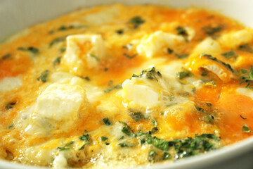 Cooking scrambled eggs with cheese and herbs