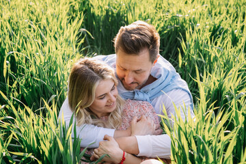 Young couple retired in nature and have great time sitting in green grass in nature