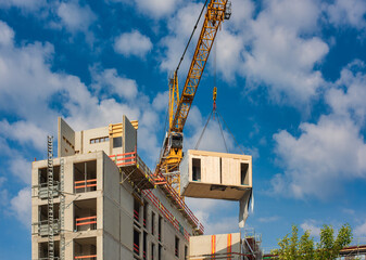 Crane lifting a wooden building module to its position in the structure. Construction site of an...