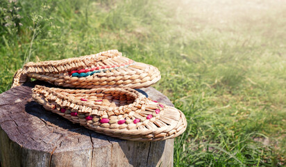 Bast shoes braided from natural materials lie on a stump on the blurred background of nature, copy...