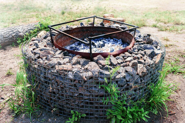 Large stone brazier well for a country house. Place for a family barbecue. - obrazy, fototapety, plakaty