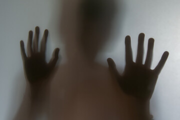 Reflection of shadows of children hands on frosted glass, blur