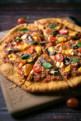 Fresh baked thin crust Italian pizza with tomato sauce pepper cheese and basil leaf on Dark rustic table background.