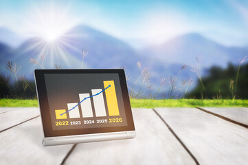 2022 to 2026 sustainable business strategy and financial growth graph stock trading on computer digital tablet on plank and mountain background. Sustainability development smart technology concept
