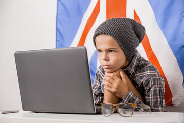 Happy   teen school student studying with laptop with english flag on the background