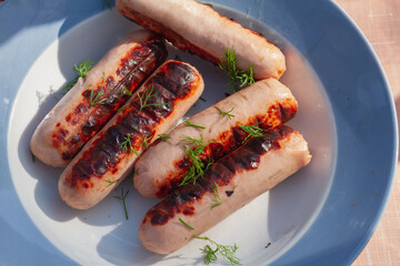 The sausages are grilled on a picnic grill and sprinkled with green dill