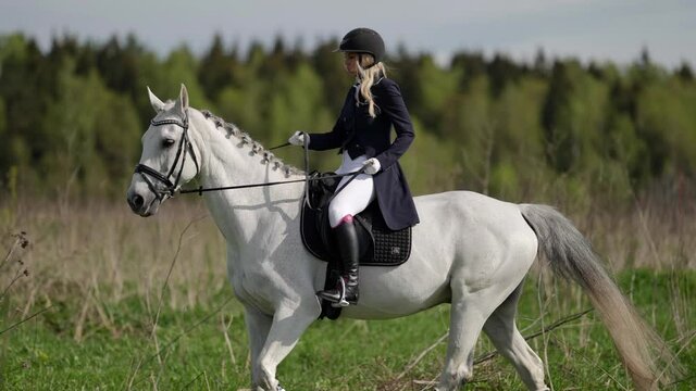 professional jockey is training on farm, riding white horse in field, sporty hobby