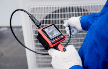 the technician uses a digital camera to check the clogging of the heat exchanger