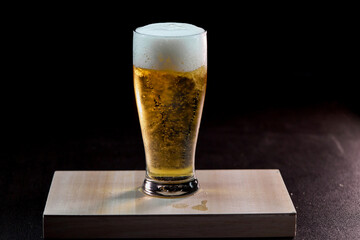 glass of beer with foam isolate on dark background