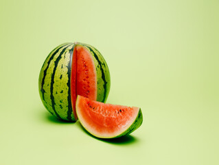 Fresh and juicy watermelon with a cut slice isolated on a pastel green background. Summer healthy...