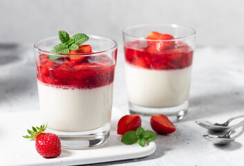 Vegan panna cotta with coconut and strawberries in glasses on gray background. Vegan food concept....