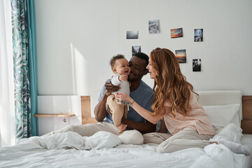 Friendly family having fun on white bed in the bedroom