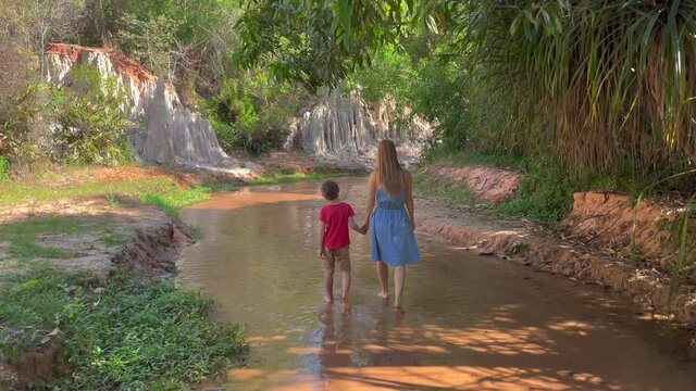 Slowmotion shot. A family walks along a red canyon or Fairy stream at the border of desert in the Mui Ne village in southern Vietnam. Shot on a phone