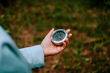 A women holds a compass in hand and is guided by the area, autumn forest, walk,hiking