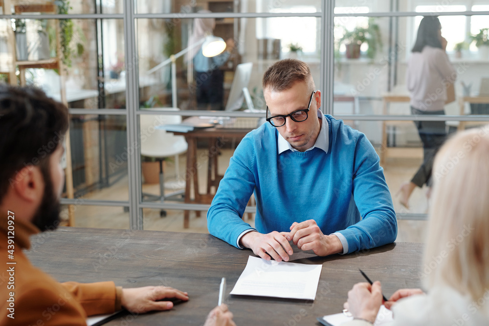 Poster handsome man reading contract at job interview