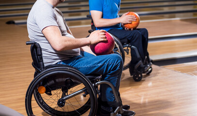 Two young disabled men in wheelchairs playing bowling in the club