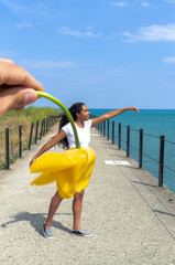 A man holds up a yellow tulip upside down by the stem in front of a mixed race African American...