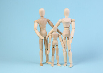 Happy family concept. Wooden puppets of mother father and child on blue background