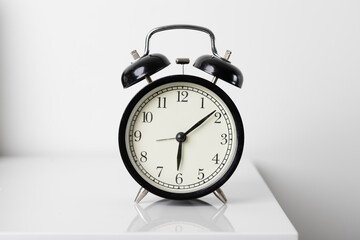black alarm clock on white table. morning time.