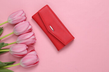 Red wallet and bouquet pink tulips on pink background. Top view