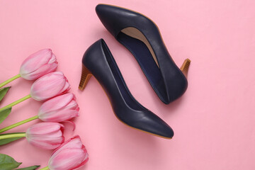 Women's shoes with heels and bouquet of pink tulips on pink background. Top view