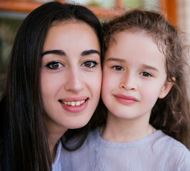 Close-up of the face of a young mother and little daughter. Similarity and kinship.