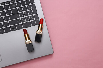 Beauty blog. Laptop with red lipstick on pink background. Top view