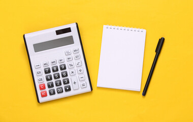 Calculator and notebook on yellow background. Top view. Flat lay