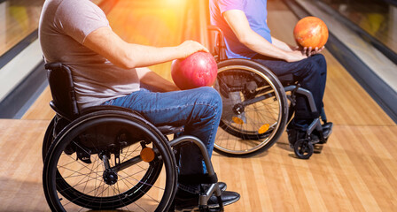 Two young disabled men in wheelchairs playing bowling in the club