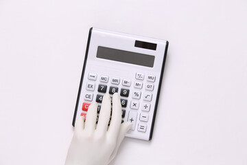 White mannequin hand using calculator on gray background