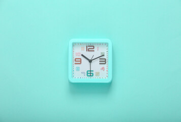 Square alarm clock on a blue background. Top view