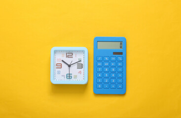 Calculator and alarm clock on yellow background. Top view
