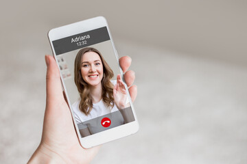 A female hand holds a mobile phone with a girl on the screen, video chat. A woman makes a video...