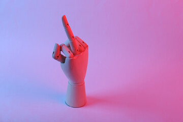 Wooden hand shows indecent middle finger gesture in pink blue gradient neon light