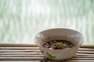 Bowl beef noodles on bamboo table against rice paddy field