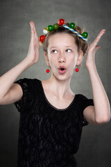 Funny teen girl with a wreath of sweets on her head fooling around in front of the camera.