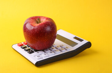 Calculator with red apple on yellow background