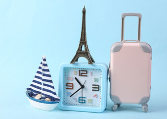 Travel time. Alarm clock with travel attributes on blue background