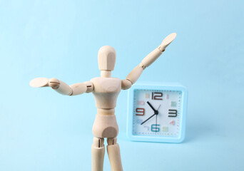 Happy Wooden puppet and alarm clock on blue background
