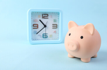 Piggy bank and Alarm clock on blue background