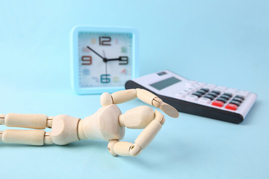 Frustrated puppet with alarm clock and calculator on blue background