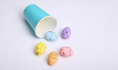 Easter composition. Cardboard cup with colored Easter eggs on white background