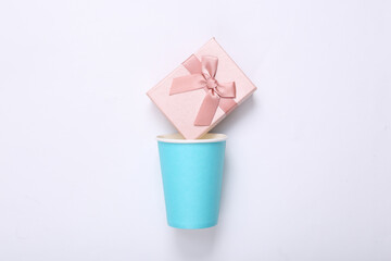 Cardboard cup with gift box on white background.