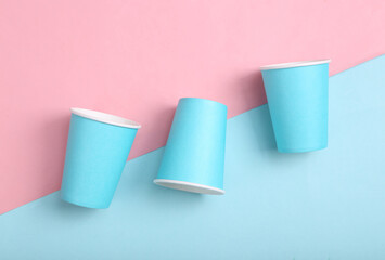 Empty blue cardboard coffee cups on pink blue background. Minimalism