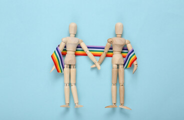 Two puppets with LGBT rainbow ribbon pride tape on blue background. Stop homophobia. Love concept