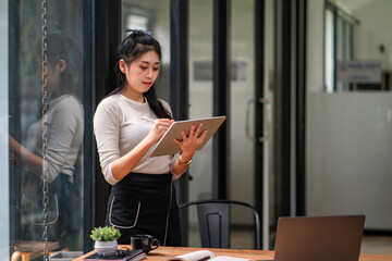 Fototapeta premium Attractive woman working on a tablet in a home office.