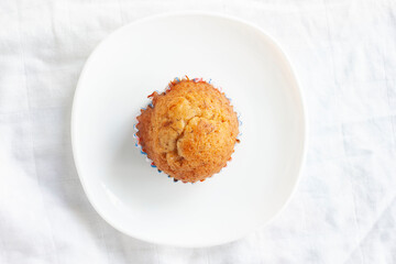 Top view of sweet banana muffins in white plate on white tablecloth.