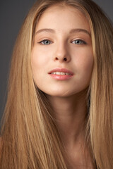 Naklejka premium Natural portrait of young beautiful teen age girl with long straight hair. Female model studio shot against grey background. Pretty girl